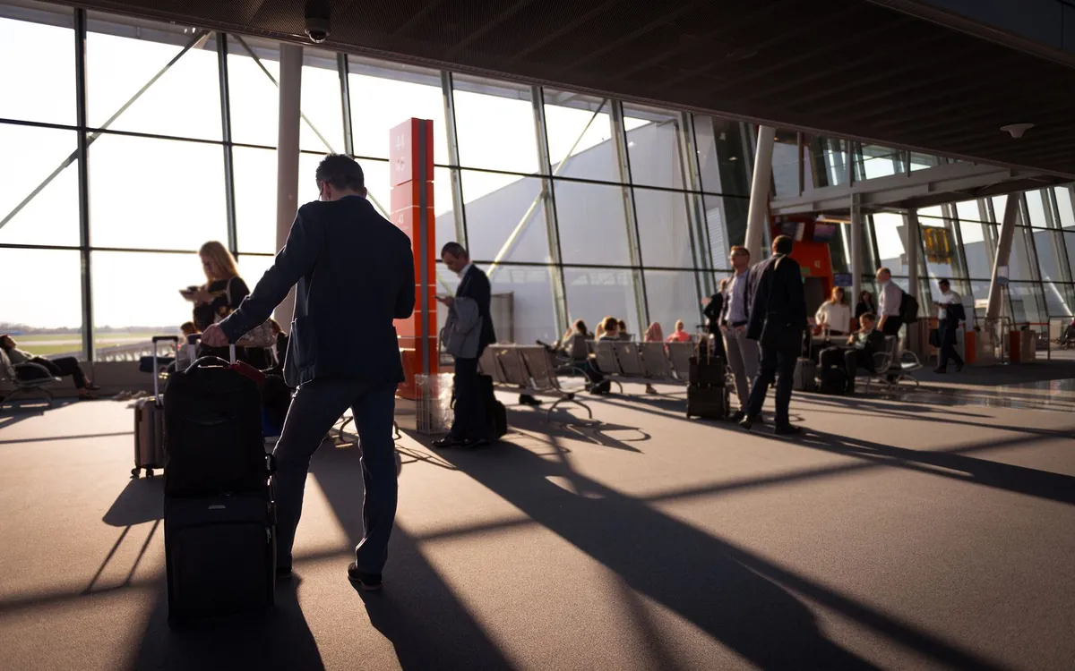 Reizigers met koffers in een zonnige vertrekhal van de luchthaven