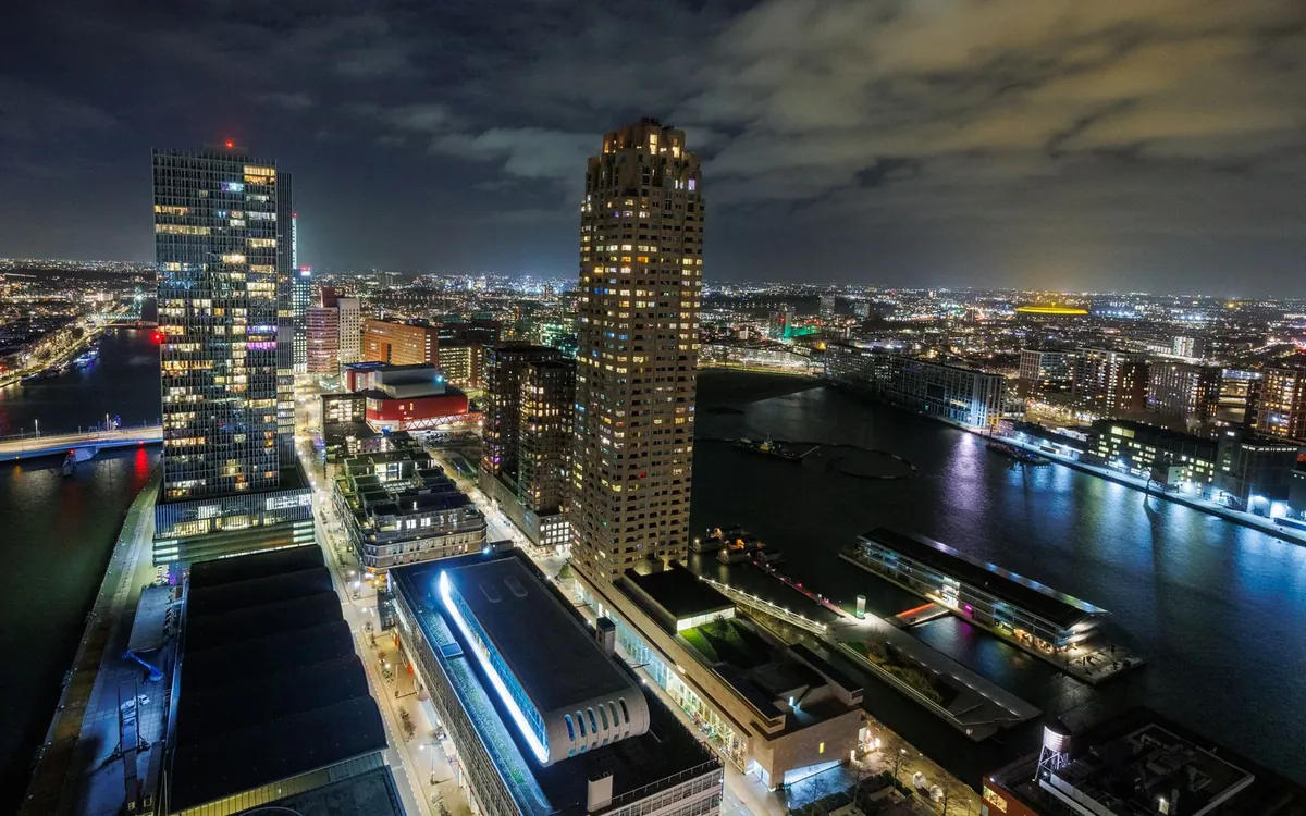 Skyline van Rotterdam bij avond met hoogbouw aan de Maas